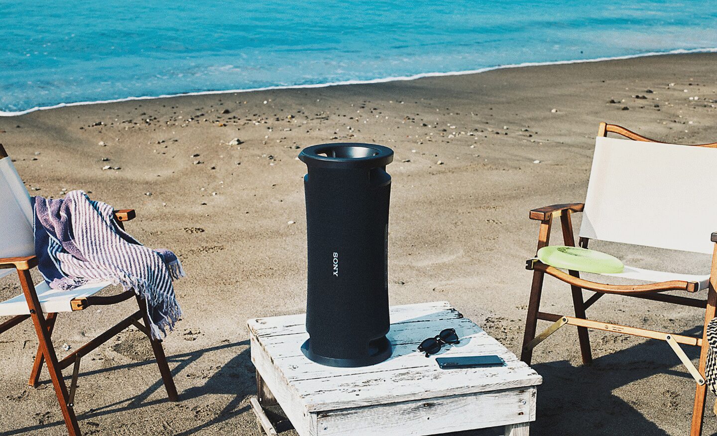 Una playa con la bocina portátil ULT FIELD 7 sobre una mesa junto a dos sillas.