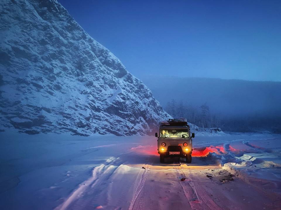 Coche en una carretera nevada junto a la montaña.