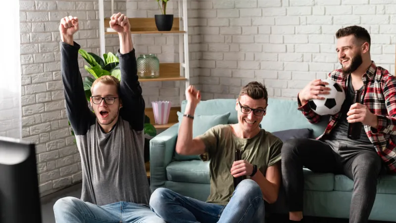 cheerful-male-friends-watching-sports-tv-with-football-beer